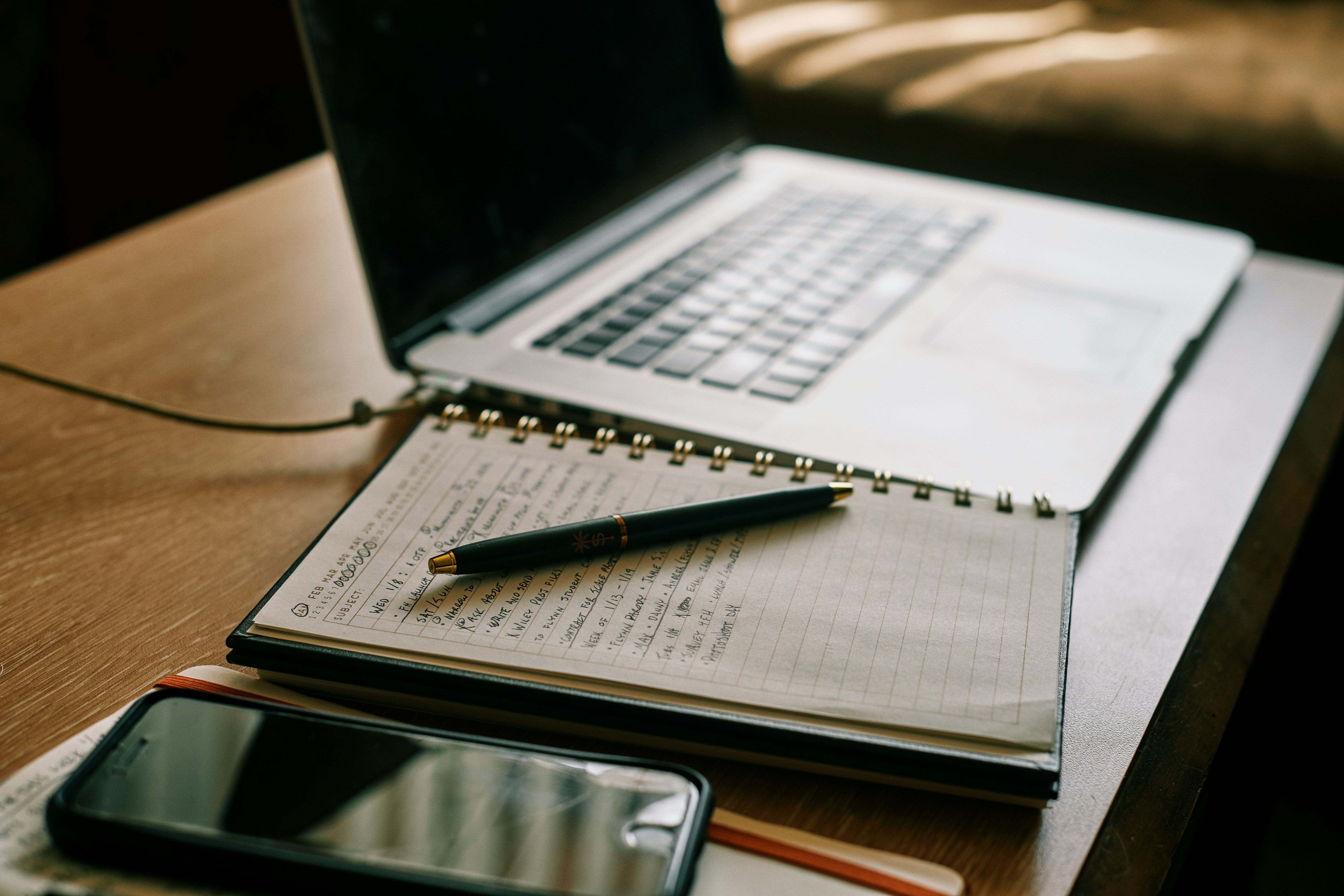 Workspace profissional com MacBook, caderno de notas e smartphone - Acompanhamento Online Personalizado